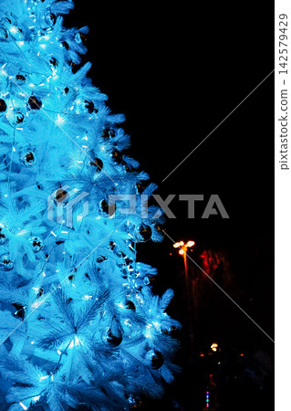 Bright blue Christmas tree with lights and ornaments during nighttime celebration Bright blue Christmas tree with lights and ornaments during nighttime celebration 142579429