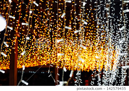 Bright lights hang from above in a festive setting during an evening gathering at a local event 142579435