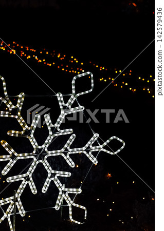 Winter decorations shown as a snowflake light display at night during a holiday celebration in a public park 142579436
