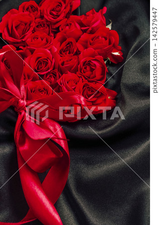 Red roses arranged on black fabric with a red ribbon during a special event Red roses arranged on black fabric with a red ribbon during a special event 142579447