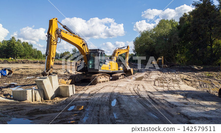 xcavator digs trenches at a construction site. Concept for laying external sewer pipes. xcavator digs trenches at a construction site. Concept for laying external sewer pipes. 142579511