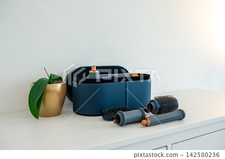 Styling kit with attachments viewed from above on white surface. Overhead view of complete hair styling kit with all attachments displayed on white surface, organized beauty technology flat lay 142580236