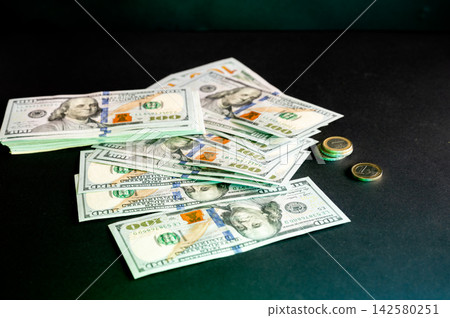Spread of Dollar Bills and Coins. A spread of US one hundred dollar bills and coins on a dark background, a conceptual image of cash, money, wealth and finance. Spread of Dollar Bills and Coins. A spread of US one hundred dollar bills and coins on a dark background, a conceptual image of cash, money, wealth and finance. 142580251