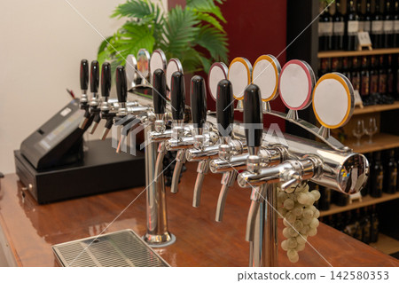 Beer taps with blank labels arranged on a wooden bar counter in a pub or brewery setting, ready for serving draft beverages to customers 142580353