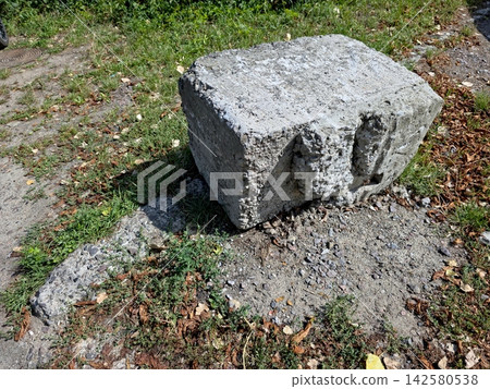 Fragment of Concrete Support Rests on Earthy Ground Surrounded by Grass Fragment of Concrete Support Rests on Earthy Ground Surrounded by Grass 142580538