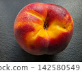 Ripe Peach Resting on a Sleek Black Surface Captures Attention and Flavor 142580549