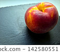 Ripe Peach Resting on Dark Slate Reflecting Sunlight in a Cozy Kitchen 142580551
