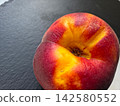 Ripe Peach Resting on a Dark Slate Surface Under Natural Light 142580552