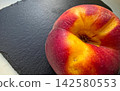 Ripe Peach Resting on a Dark Slate Inviting and Deliciously Vibrant 142580553