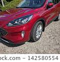 Shiny Red Car Parked on a Sunny Day Surrounded by Lush Greenery 142580554
