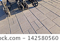 Scooter Wheels Resting on a Textured Sidewalk Under the Warm Sunlight 142580560