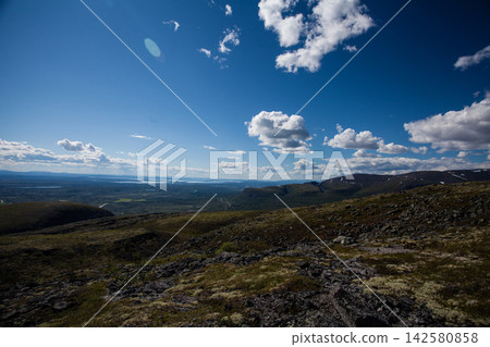 Wide summer landscape from the Khibiny Mountains in Murmansk Region, Russia, showing a rocky mountain slope covered with lichen and low subarctic vegetation above the forested lowlands of the Kola Pen Wide summer landscape from the Khibiny Mountains in Murmansk Region, Russia, showing a rocky mountain slope covered with lichen and low subarctic vegetation above the forested lowlands of the Kola Pen 142580858