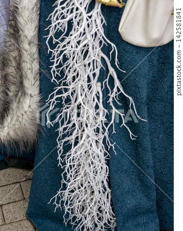 Detailed view of costume feature with white artificial decorations on teal fabric and grey faux fur Detailed view of costume feature with white artificial decorations on teal fabric and grey faux fur 142581841
