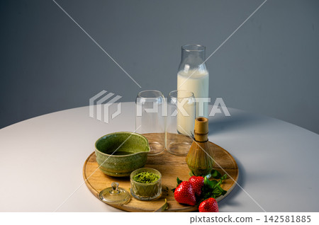 Multiple Matcha Beverages Arranged on Tray, Cafe Display. Multiple matcha beverages in different glasses arranged on wooden tray with ceramic bowl and strawberries. Cafe-style display with bamboo Multiple Matcha Beverages Arranged on Tray, Cafe Display. Multiple matcha beverages in different glasses arranged on wooden tray with ceramic bowl and strawberries. Cafe-style display with bamboo 142581885