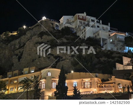 illuminated residential buildings on a hilly landscape at night with serene and peaceful atmosphere, concrete and brick structures against a white and yellow backdrop. illuminated residential buildings on a hilly landscape at night with serene and peaceful atmosphere, concrete and brick structures against a white and yellow backdrop. 142582500
