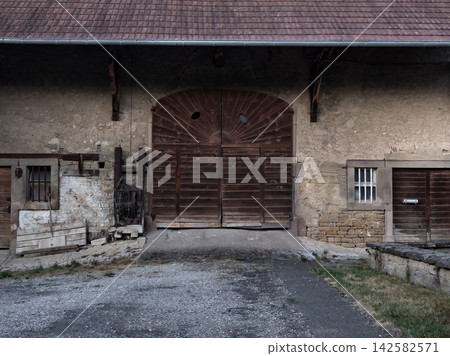 old rustic barn door with wooden planks and stone wall in rural farmhouse setting frontal view brown and gray tones natural light clean background copy space editorial use. 142582571