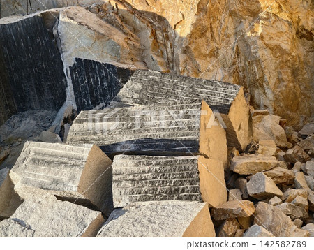Crushed concrete blocks and rugged rocky rubble piled against quarry wall amid construction debris and heavy masonry fragments in natural stone quarry setting, sunlit textures Crushed concrete blocks and rugged rocky rubble piled against quarry wall amid construction debris and heavy masonry fragments in natural stone quarry setting, sunlit textures 142582789