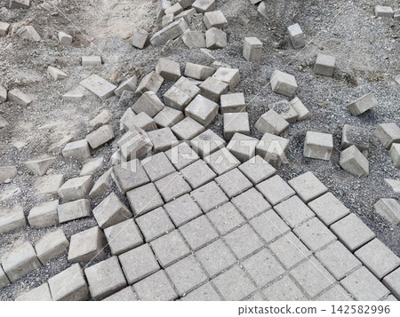 Massive pile of concrete paving blocks scattered across gravel construction site exposing rough texture and industrial urban composition, with concrete, block, paving, stone detail Massive pile of concrete paving blocks scattered across gravel construction site exposing rough texture and industrial urban composition, with concrete, block, paving, stone detail 142582996