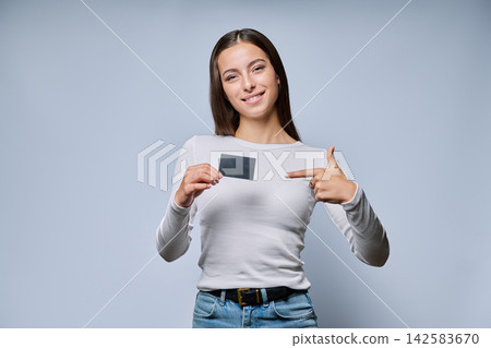 Smiling woman holding black plastic transport card on grey background Smiling woman holding black plastic transport card on grey background 142583670