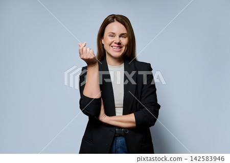 Smiling adult businesswoman showing money gesture with fingers looking at camera on grey background Smiling adult businesswoman showing money gesture with fingers looking at camera on grey background 142583946
