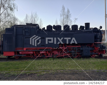 Restoration crew reviews preservation plans for nostalgic industrial steam engine surrounded by trees Restoration crew reviews preservation plans for nostalgic industrial steam engine surrounded by trees 142584217