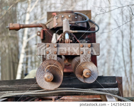 Decaying metal and weathered wood. Corroded winch with textured metal and weathered natural background Decaying metal and weathered wood. Corroded winch with textured metal and weathered natural background 142584228