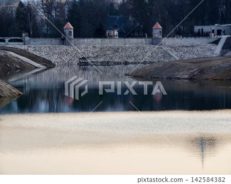 City water mirror. Quiet urban water scene. Serene urban water body mirroring structures and subdued sky City water mirror. Quiet urban water scene. Serene urban water body mirroring structures and subdued sky 142584382