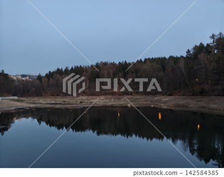 Calm water with fishing tranquility. Silent twilight reflections on water with angler nearby Calm water with fishing tranquility. Silent twilight reflections on water with angler nearby 142584385