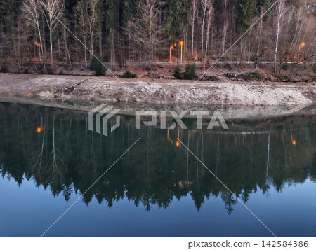 Sensitive image of evening water reflecting tree outlines with balanced composition and soothing colors Sensitive image of evening water reflecting tree outlines with balanced composition and soothing colors 142584386