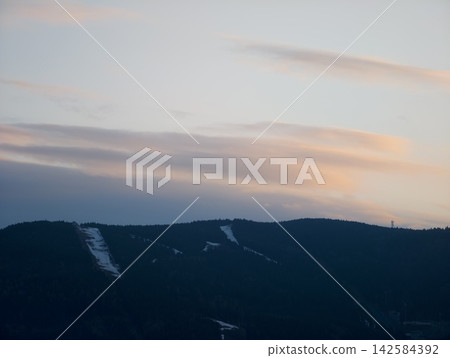 Serene twilight over snowy mountain peaks. Calm dusk scene with distant ski routes and shadowed summits Serene twilight over snowy mountain peaks. Calm dusk scene with distant ski routes and shadowed summits 142584392