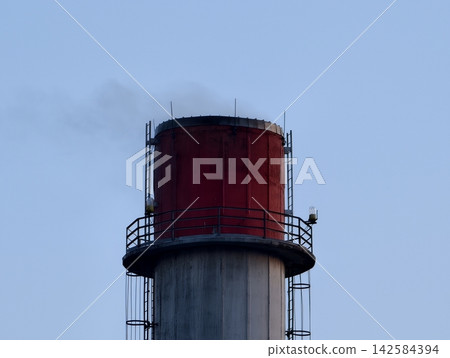 Industrial smokestack with circular platform and ladder emphasizes maintenance access and architectural design Industrial smokestack with circular platform and ladder emphasizes maintenance access and architectural design 142584394