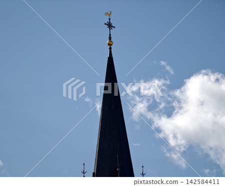 Church tower artistry. Photographers capture peaceful view of ancient church with ornate gothic details Church tower artistry. Photographers capture peaceful view of ancient church with ornate gothic details 142584411