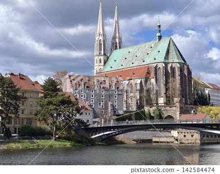 Evening church glow. Serene scene with sunlight illuminating historic rooftops and gentle breezes 142584474