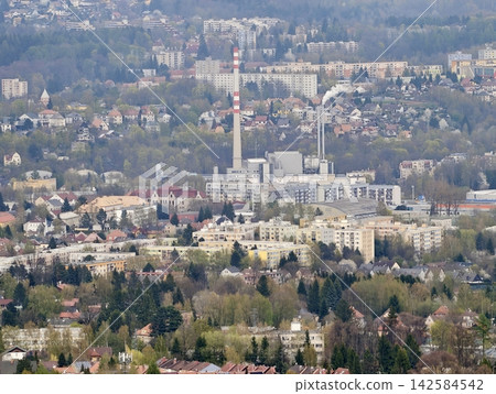 Factories and smokestacks near homes. Industrial emissions and urban landscape interweave visibly Factories and smokestacks near homes. Industrial emissions and urban landscape interweave visibly 142584542