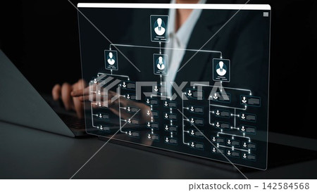 A businesswoman works on a laptop displaying a transparent organizational chart, demonstrating modern technology and data visualization in a professional office setting. Sigmoid A businesswoman works on a laptop displaying a transparent organizational chart, demonstrating modern technology and data visualization in a professional office setting. Sigmoid 142584568