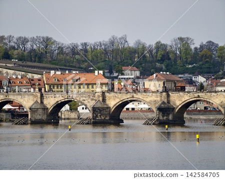 City river scene. Urban arches over flowing waters. Sunlit bridges shelter bustling city life City river scene. Urban arches over flowing waters. Sunlit bridges shelter bustling city life 142584705