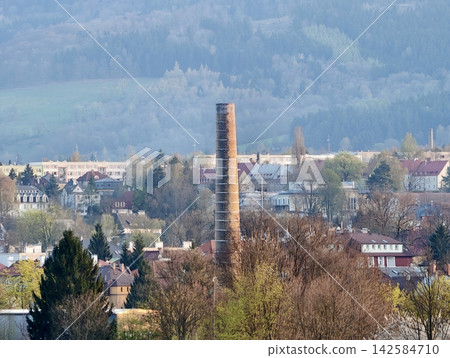 Urban chimney amidst peaceful neighborhood. Residential rooftops and hills surround historic chimney Urban chimney amidst peaceful neighborhood. Residential rooftops and hills surround historic chimney 142584710