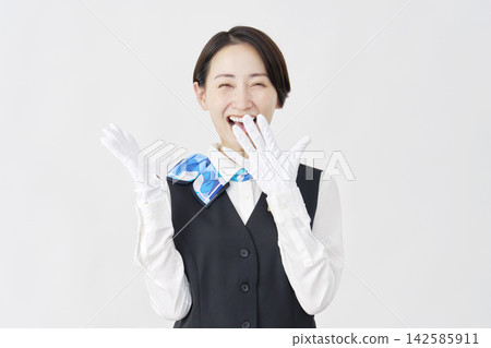 一位面帶微笑、略帶驚訝的女工作人員(接待員/巴士導遊)站在白色背景上。 一位面帶微笑、略帶驚訝的女工作人員(接待員/巴士導遊)站在白色背景上。 142585911