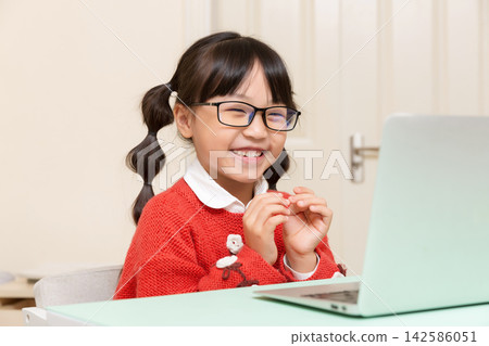 happy Asian schoolgirl using laptop, smiling child studying online at home, e-learning and education concept happy Asian schoolgirl using laptop, smiling child studying online at home, e-learning and education concept 142586051