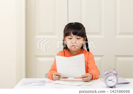 A young female student held her exam paper with a disappointed look on her face.The words on the notebook read: "Homework". A young female student held her exam paper with a disappointed look on her face.The words on the notebook read: "Homework". 142586098