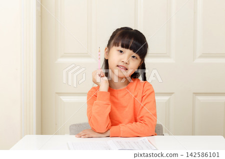 Inspired young girl holding a pencil up as she gets a creative idea. 142586101