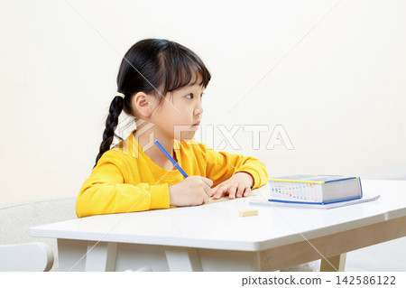 Cute Asian Girl Thinking While Studying at Desk, Homework and Learning Concept Cute Asian Girl Thinking While Studying at Desk, Homework and Learning Concept 142586122