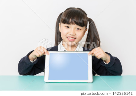 Smiling Asian school girl showing tablet with blank screen, digital learning and education technology concept, studio isolated on white background 142586141