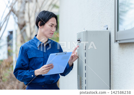 一名男性工人正在檢查熱水器。 一名男性工人正在檢查熱水器。 142586238