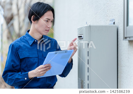 一名男性工人正在檢查熱水器。 一名男性工人正在檢查熱水器。 142586239