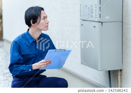 一名男性工人正在檢查熱水器。 一名男性工人正在檢查熱水器。 142586241