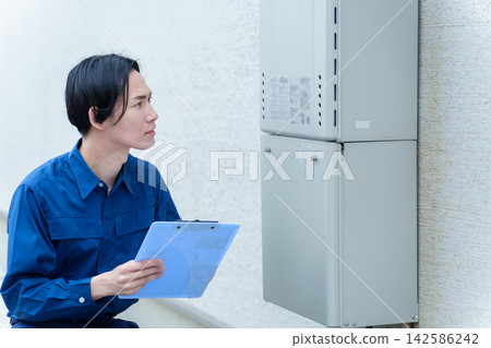 一名男性工人正在檢查熱水器。 一名男性工人正在檢查熱水器。 142586242