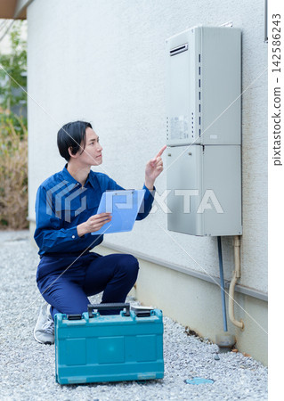 一名男性工人正在檢查熱水器。 一名男性工人正在檢查熱水器。 142586243