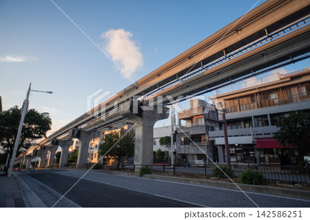 在陽光明媚的日子裡,沖繩 Yui Rail 單軌列車的道路和軌道兩旁林立著建築物。 在陽光明媚的日子裡,沖繩 Yui Rail 單軌列車的道路和軌道兩旁林立著建築物。 142586251