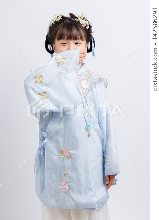 Medium shot of an innocent girl in ancient Chinese attire looking down thoughtfully during a studio photoshoot. Medium shot of an innocent girl in ancient Chinese attire looking down thoughtfully during a studio photoshoot. 142586291